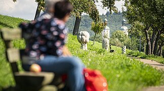 Zwei Wanderer auf einer Bank am Andachtsweg zur Wallfahrtsbasilika Maria Brünnlein.