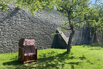 Strandkörbe im Stadtgraben Ein Strandkorb steht auf der grünen Wiese im Stadtgraben. Bäume spenden Schatten.