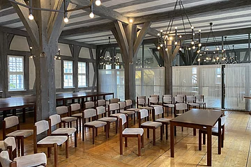 Blick in einen festlich beleuchteten Saal mit Holzboden und historischem Ambiente.