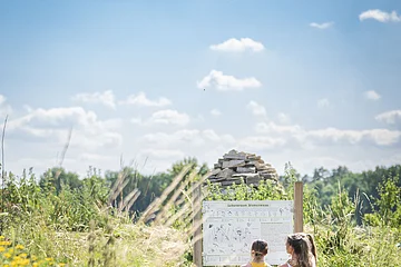 Eine Familie betrachtet eine Informationstafel im botanischen Obstlehrgarten.
