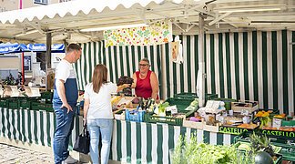 Ein Paar kauft am Wochenmarkt in Wemding bei einem Verkaufsstand ein.