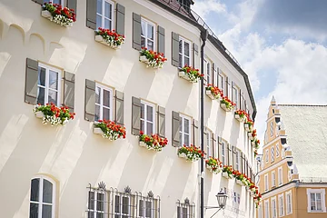 Das Verwaltungsgebäude von außen im Sommer mit Blumenkästen an den Fenstern.