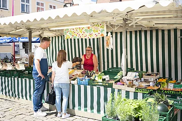 Ein Paar kauft am Wochenmarkt in Wemding bei einem Verkaufsstand ein.