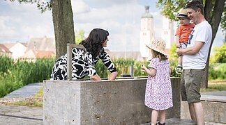 Eine Frau testet das Handkneippbecken am Johannisweiher. Der Mann und die beiden Kinder sehen ihr dabei zu.