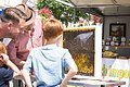 Drei Personen betrachten einen Honigwaben vom Bienenzuchtverein auf dem Wochenmarkt in Wemding.