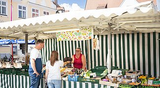 Ein Paar kauft am Wochenmarkt in Wemding bei einem Verkaufsstand ein.