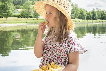 Mädchen isst Pommes auf der Seeterrasse am Waldsee.