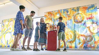 Eine Familie sieht sich im KunstMuseum ein Kunstwerk an.