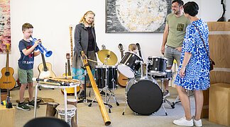 Eine Familie testet während einer Führung im KunstMuseum die Musikinstrumente.