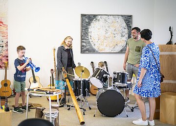 Eine Familie testet während einer Führung im KunstMuseum die Musikinstrumente.