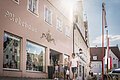 Eine Familie spaziert entlang dem Modehaus Britzelmeir am historischen Marktplatz.