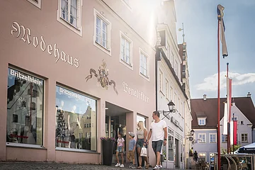 Eine Familie spaziert entlang dem Modehaus Britzelmeir am historischen Marktplatz.