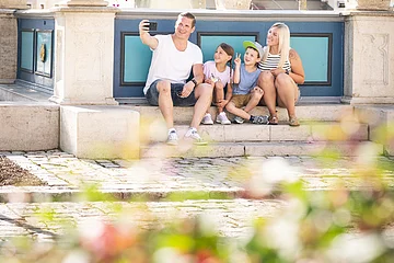 Familie macht ein Selfie am historischen Marktplatz. Im Hintergrund ist der Marienbrunnen zu sehen.