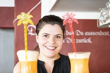Barkeeperin hält zwei Cocktails in der Hand.