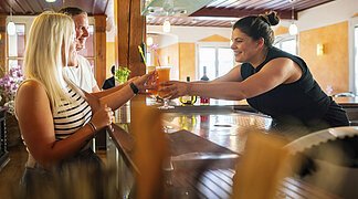 Barkeeperin übergibt zwei Gästen einen Cocktail.