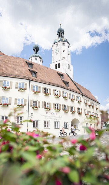 Zwei Radfahrer fahren am Verwaltungsgebäude mit ihrem Fahrrad vorbei.