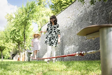 Eine Frau hilft ihrem Kind beim balancieren auf der Slackline im Stadtgraben.
