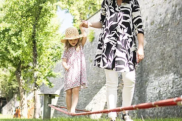 Eine Mama hilft ihrem Kind beim balancieren auf der Slackline im Stadtgraben.