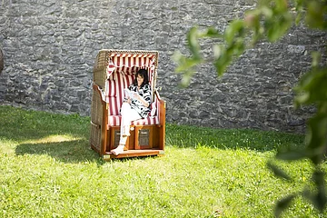 Eine Frau sitzt im Strandkorb im Stadtgraben und liest ein Buch.