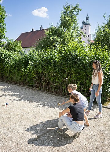 Eine Mutter spielt mit ihren beiden Kindern auf dem Bocciafeld im Johannisgraben.