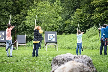 Eine Familie steht mit Pfeil und Bogen auf einer Wiese.