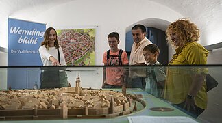 Eine Stadtführerin zeigt einer Familie während einer Stadtführung das Altstadtmodell im Haus des Gastes.