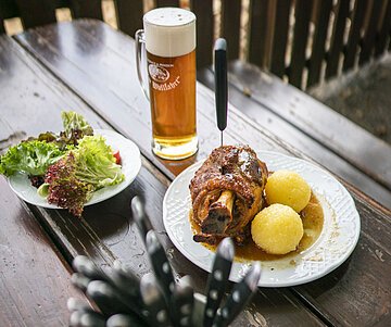 Biergarten Eine Schweinshaxe mit Pilgertrunk aus dem Biergarten in Wemding.