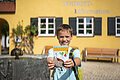 Ein Kind hält die Broschüre "Entdecke Wemding" hoch. Im Hintergrund ist die Tourist-Information zu erkennen.