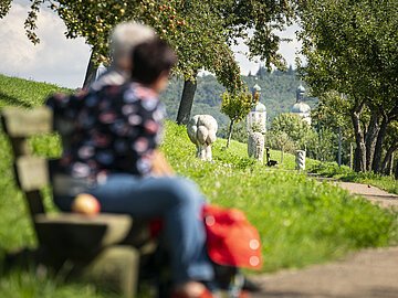 Andachtsweg zur Wallfahrtsbasilika Maria Brünnlein Ein Ehepaar sitzt auf einer Bank am Andachtsweg.