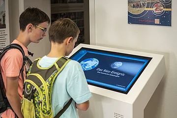 Kinder schauen sich die Ries-Animation in der Geopark-Infostelle an.