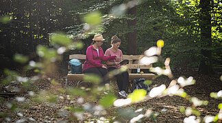 Zwei Frauen sitzen auf einer Bank beim Waldbaden in Wemding.