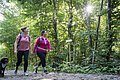 Zwei Freundinnen gehen mit ihrem Hund im Wald spazieren.