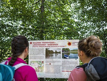 Informationstafel Sagenweg am Waldsee Zwei Freundinnen lesen die Informationstafel "Sagenweg" am Waldsee.