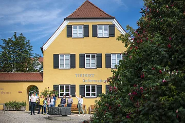 Die Stadtführerin ist mit einer Gruppe am Mangoldbrunnen vor der Tourist-Information.
