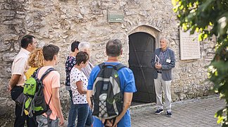Ein Stadtführer stellt den Folterturm während einer Stadtführung einer Gruppe vor.