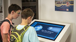 Kinder schauen sich die Ries-Animation in der Geopark-Infostelle an.