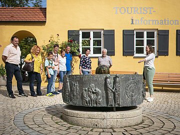 Stadtführung an der Tourist-Info Stadtführerin zeigt ihrer Gruppe den Mangoldbrunnen während einer Stadtführung.