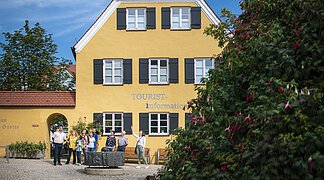 Die Stadtführerin ist mit einer Gruppe am Mangoldbrunnen vor der Tourist-Information.