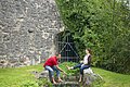 Ein Ehepaar sitzt am Bach des Stadtgrabens und hängt die Füße in das Wasser.
