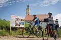 Zwei Radfahrer fahren an der Informationstafel des Sagenwegs vorbei.