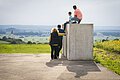 Die Kinder sitzen auf den Steinen der Zeitpyramide und die Eltern stehen daneben. Gemeinsam blicken sie in das Ries und genießen den tollen Ausblick.
