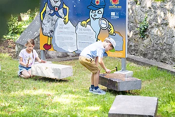 Kinder spielen an der Kinder-Erlebnisstation am Kreuzgraben mit Klangsteinen.