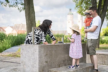 Eine Frau testet das Handkneippbecken am Johannisweiher. Der Mann und die beiden Kinder sehen ihr dabei zu.