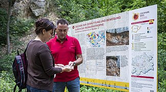 Ein Paar steht vor einer Informationstafel im Steinbruch.