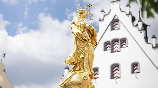 Die goldene Marien Statue vom Marienbrunnen am historischen Marktplatz ist im Vordergrund des Fotos.