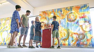 Eine Familie sieht sich im KunstMuseum ein Kunstwerk an.