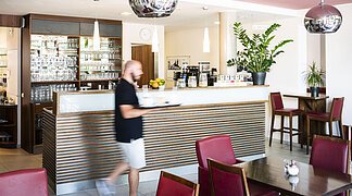 Ein Mann läuft zu den Tischen im Lieblingsgrieche und bedient die Gäste.