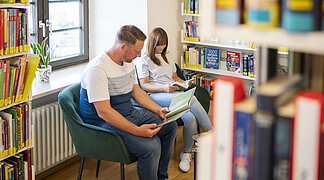 Ein Paar ließt Bücher in der Stadtbücherei.