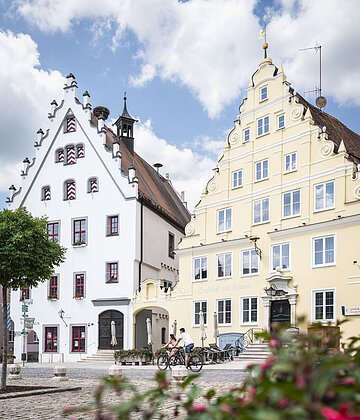 Zwei Radfahrer fahren am historischen Rathaus vorbei.