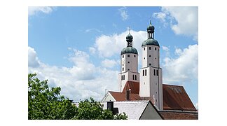 Blick auf die Türme der Stadtpfarrkirche mit weiß blauem Himmel